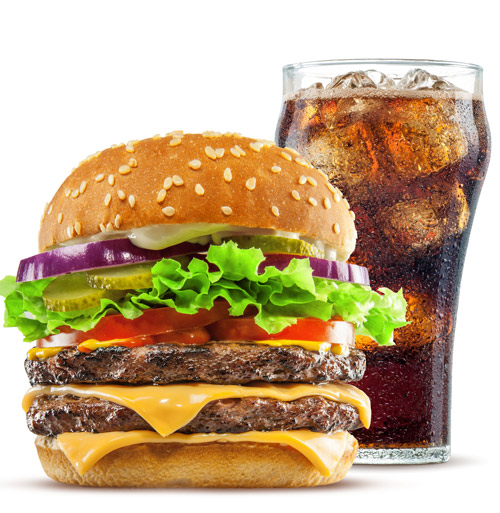 A double cheeseburger with lettuce, tomato, pickles, onions, and a sesame seed bun sits in front of a glass of cola filled with ice—just one of the mouthwatering meals you can savor at River Rock Casino Resort.